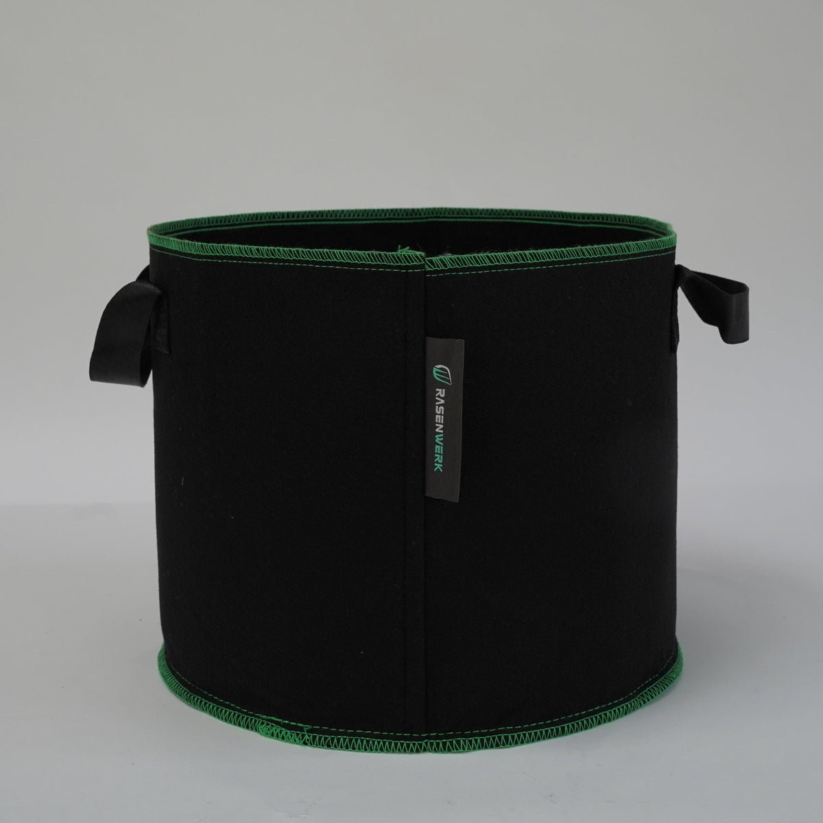 Schwarze Pflanztasche aus Vliesstoff mit zwei Griffen und grüner Randnaht, leer, Studiofoto