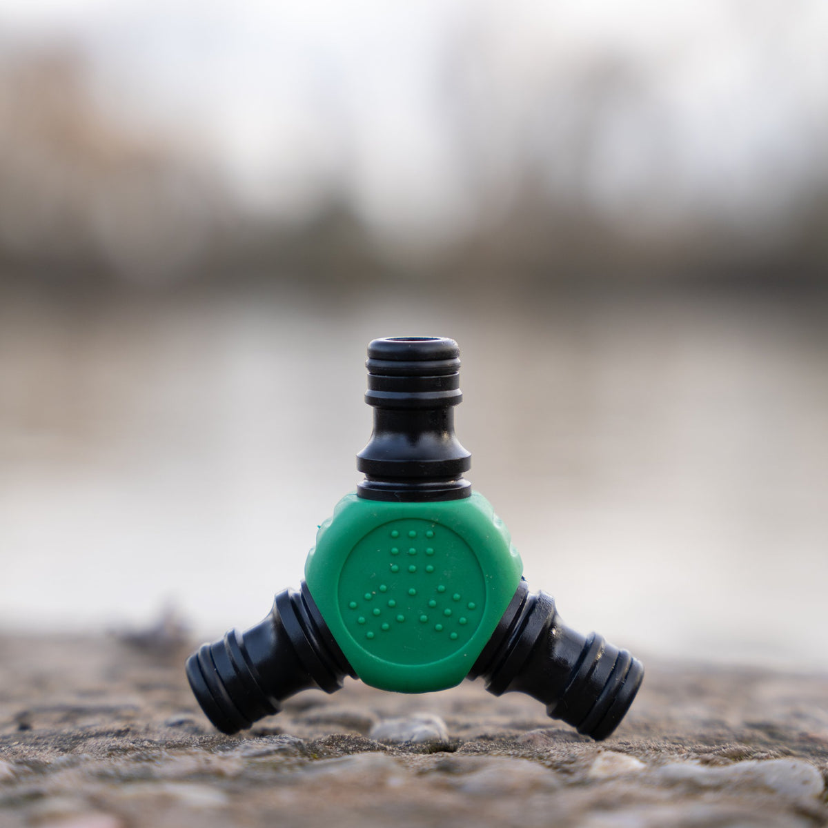 Y-Verbinder auf einem Stein, Wasser und Ufer unscharf im Hintergrund