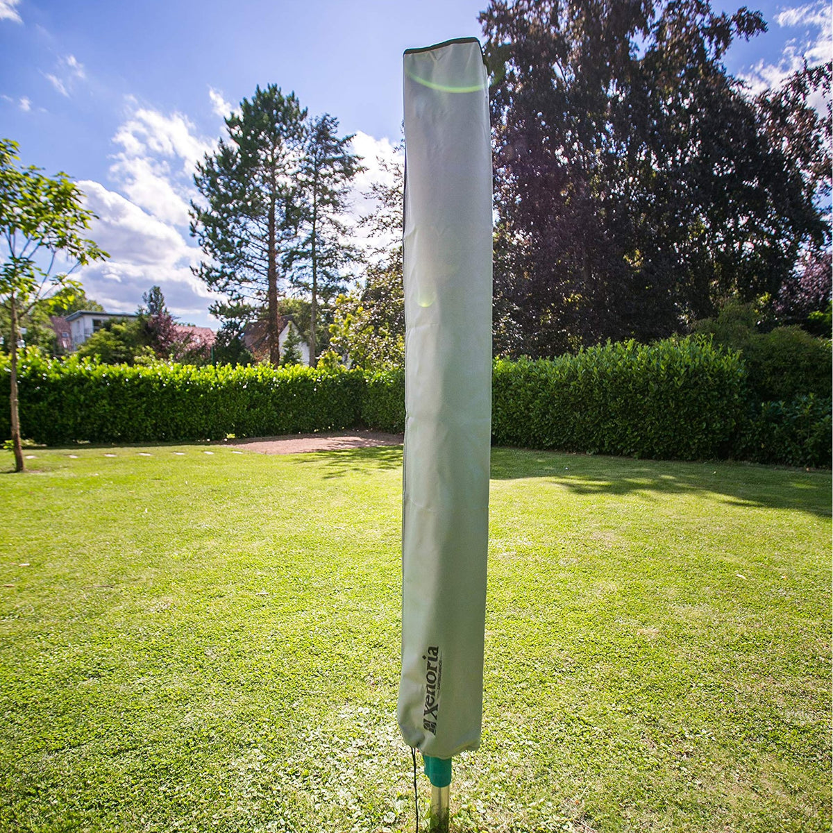 Zusammengeklappte Wäschespinne mit graugrüner Xenoria Schutzhülle im Garten auf dem Rasen